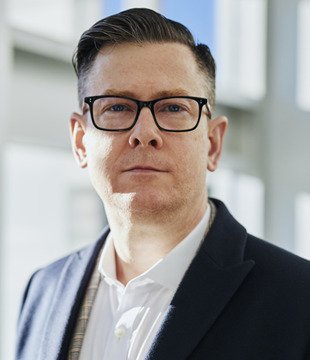 Headshot of a man wearing glasses and a blazer
