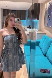 Young woman in a denim dress taking a selfie.