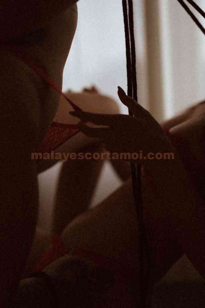 Close-up of a person's hand gently touching red lace lingerie.